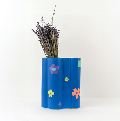Stickers fleurs colorées, collés sur un vase bleu.